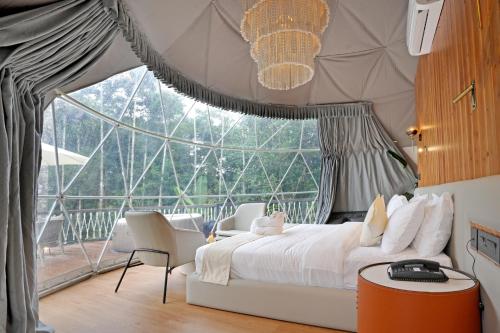 a bedroom with a bed and a large window at Le Villagio Resort & Domes in Sultan Bathery