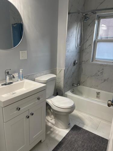 La salle de bains blanche est pourvue d'un lavabo, de toilettes et d'une baignoire. dans l'établissement Boston Luxury Condo Style Rooms, à Boston