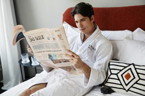 een man in bed die een krant leest bij HOTEL VITE - By Naman Hotellerie in Rome