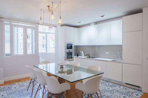 cocina con mesa de cristal y armarios blancos en Feel Porto Downtown Apartments & Studios, en Oporto