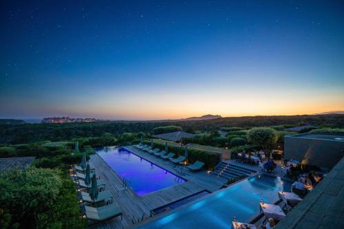 uitzicht op een zwembad in een resort 's nachts bij Hôtel & Spa Version Maquis Citadelle in Bonifacio