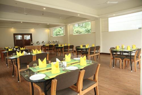 - une salle à manger avec des tables et des chaises avec des serviettes jaunes dans l'établissement Peppervine Hotel, à Thekkady