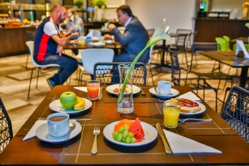 een houten tafel met borden eten erop bij Wyndham Garden Ribeirão Preto Convention in Ribeirão Preto