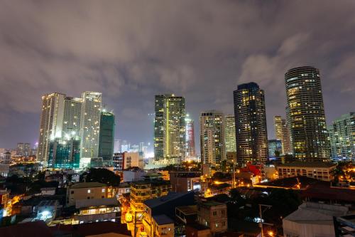 eine Skyline der Stadt in der Nacht mit hohen Gebäuden in der Unterkunft Nest Nano Suites Poblacion - Makati in Manila