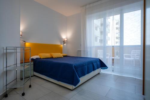 um quarto com uma cama com lençóis azuis e uma janela em Kalbia Apartment or Rooms Renovated, functional, intimate and more em Cagliari