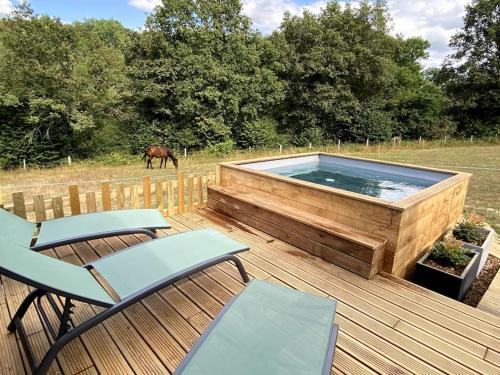 einen Whirlpool auf einer Terrasse mit einem Pferd auf einem Feld in der Unterkunft La Cabane du Petit Moulin in Bressuire