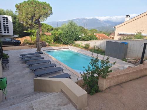 a swimming pool with lounge chairs next to a house at Edith et Jean-Paul in Porto-Vecchio