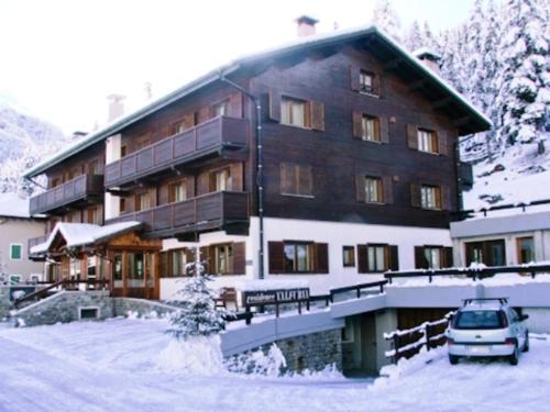 ein großes Gebäude mit einem Auto im Schnee in der Unterkunft Residence Valfurva in Santa Caterina Valfurva