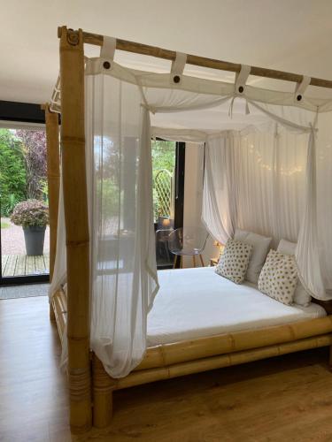 Schlafzimmer mit Himmelbett und weißen Vorhängen in der Unterkunft L'Hôtié de Brocéliande à Paimpont, au coeur des sites naturels et légendaires in Paimpont