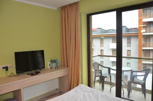 una camera da letto con TV e un balcone con tavolo di Orbi Palace Deluxe Bakuriani Room 406 a Bakuriani