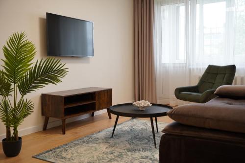 ein Wohnzimmer mit einem TV, einem Sofa und einem Tisch in der Unterkunft Sonata apartment in Panevėžys