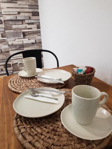 une table en bois avec des assiettes et des tasses dessus dans l'établissement Hostal Lago Cóndor, à Puerto Natales