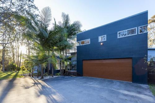 a blue house with a garage and a palm tree at Springbank House in Jindy Andy