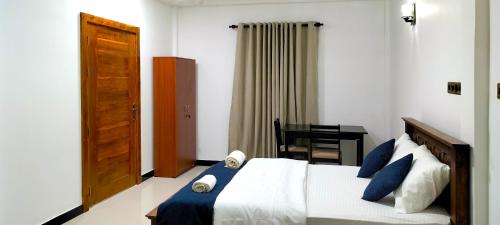 Un dormitorio con una cama con almohadas azules y una mesa. en Jaffna Inn, en Jaffna