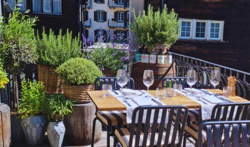 a table with wine glasses on a balcony with plants at Unique Hotel Post in Zermatt