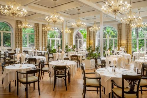 une salle à manger avec des tables, des chaises et des lustres blancs dans l'établissement Villa Bavaria, à Merano