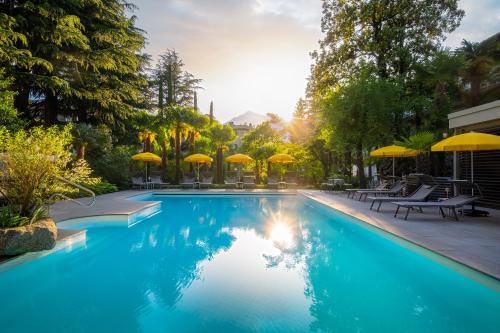 - une piscine avec des parasols, des tables et des chaises dans l'établissement Villa Bavaria, à Merano