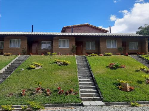 une maison avec un jardin en face dans l'établissement Chalés Bem-me-quer Itaipava, à Itaipava