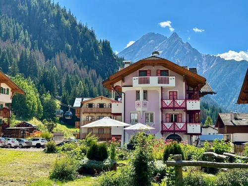 a large pink building in front of a mountain at Cesa Planber Apartments Mountain View SKI-IN SKI-OUT in Canazei