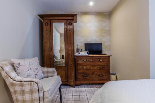 een slaapkamer met een tv, een stoel en een dressoir bij Yewfield Vegetarian Guest house in Ambleside