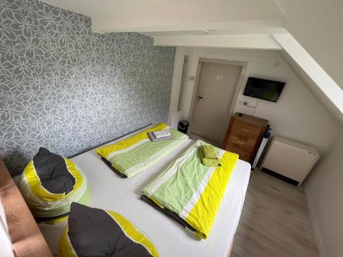 - une petite chambre avec 2 lits et une télévision dans l'établissement Pension Alpenrose, à Bad Schandau