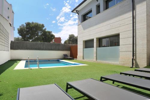 a backyard with a swimming pool and grass at Hotel Sitges in Sitges