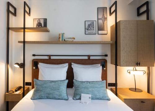 a bedroom with a bed with two blue pillows at Esteem Tour Eiffel in Paris