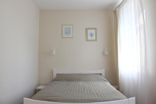 a white bedroom with a bed and a window at Apartamenti Starp Krastiem 2 in Liepāja