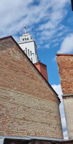 un bâtiment blanc derrière un bâtiment en briques dans l'établissement Petro delux apartments, à Kaunas