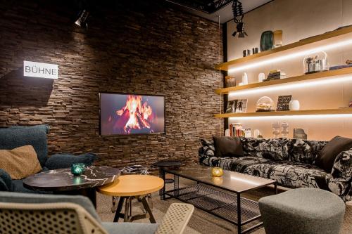 a living room with a couch and a tv on a brick wall at Motel One Stuttgart-Mitte in Stuttgart