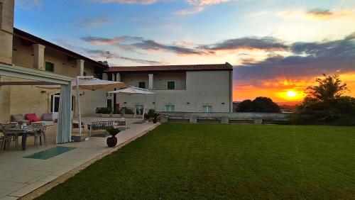 uma casa com um relvado com um pôr-do-sol ao fundo em Hotel Cave Del Sole em Matera