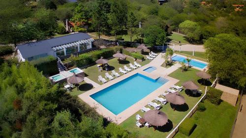 uma vista superior para uma piscina com cadeiras e guarda-sóis em Aldea de los Pajaros em Villa General Belgrano