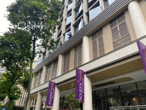 Aqueen Prestige Hotel Jalan Besar في سنغافورة: مبنى توجد أمامه لافتات أرجوانية