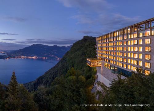 un edificio en una montaña con vistas al agua en Bürgenstock Hotel & Alpine Spa, en Bürgenstock