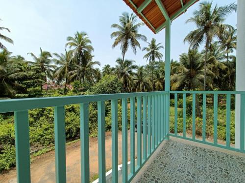 a balcony of a house with palm trees in the background at Beseco Bed and Breakfast in Benaulim