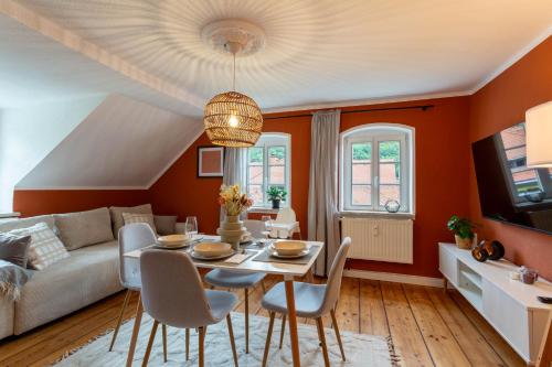 een woonkamer met oranje muren en een tafel en stoelen bij Moderne Ferienwohnung mit Festungsblick im Zentrum in Königstein an der Elbe