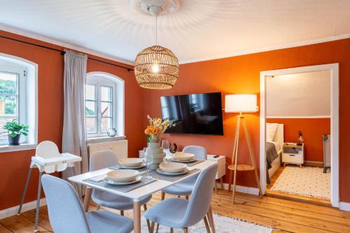 een eetkamer met oranje muren en een tafel en stoelen bij Moderne Ferienwohnung mit Festungsblick im Zentrum in Königstein an der Elbe