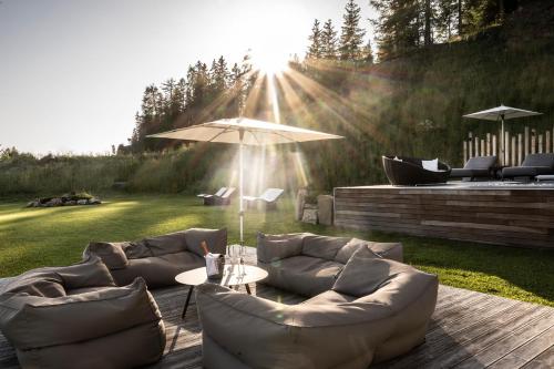 un patio con 2 sofás y una mesa con sombrilla en Hotel Schmung, en Alpe di Siusi