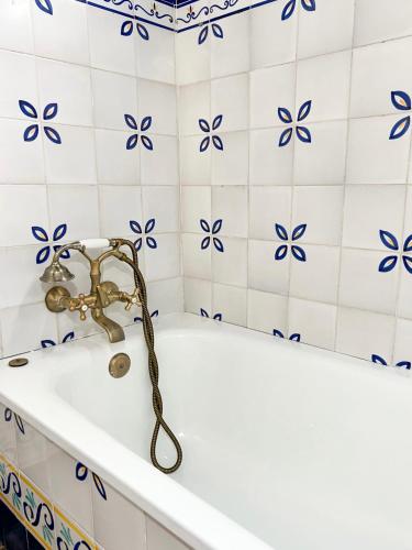 La salle de bains est pourvue d'une baignoire et de carrelage bleu et blanc. dans l'établissement Hotel Servilia, à Carmona