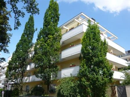 a tall building with trees in front of it at Hotel Biederstein am Englischen Garten in Munich