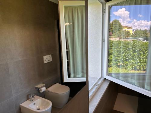 een badkamer met een toilet, een wastafel en een raam bij Hotel Riviera in Magnano in Riviera