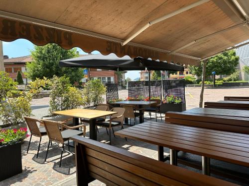 een patio met tafels en stoelen en een parasol bij Hotel Riviera in Magnano in Riviera