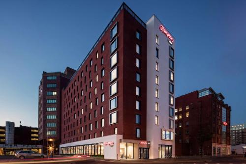 d'un grand bâtiment rouge avec un panneau. dans l'établissement Hampton By Hilton Belfast City Centre, à Belfast