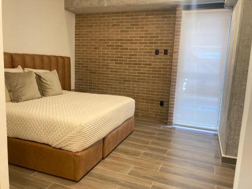 a bedroom with a bed and a brick wall at Punto Panamericano in Guadalajara