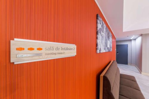 une chambre dotée d'un mur orange et d'un panneau. dans l'établissement Hampton By Hilton Iasi, à Iaşi