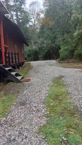 uma estrada de cascalho ao lado de uma casa e um edifício em Agradable Cabaña inserta en bosque nativo em Pucón