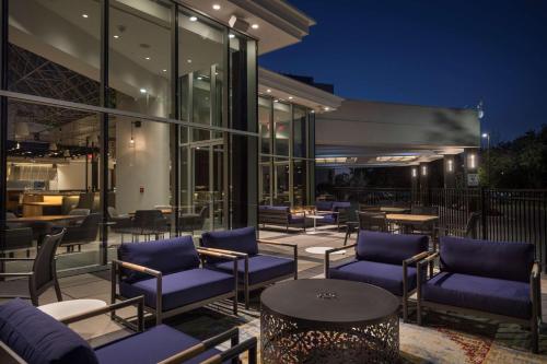 une terrasse avec des chaises et des tables bleues en face d'un bâtiment dans l'établissement Hilton Boston-Woburn, à Woburn