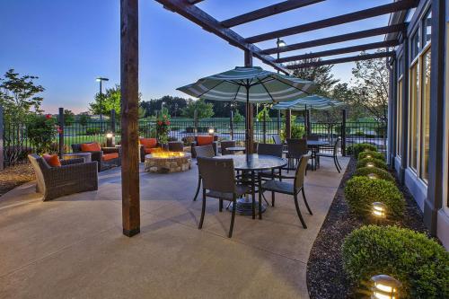 een patio met een tafel en stoelen en een parasol bij Hilton Garden Inn Akron-Canton Airport in North Canton