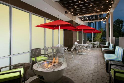 een patio met tafels en stoelen en rode parasols bij Home2 Suites by Hilton Arundel Mills BWI Airport in Hanover