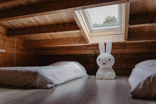 a white bunny sitting in a bedroom with two beds at Life & Cooking Holiday Home in Ermelo